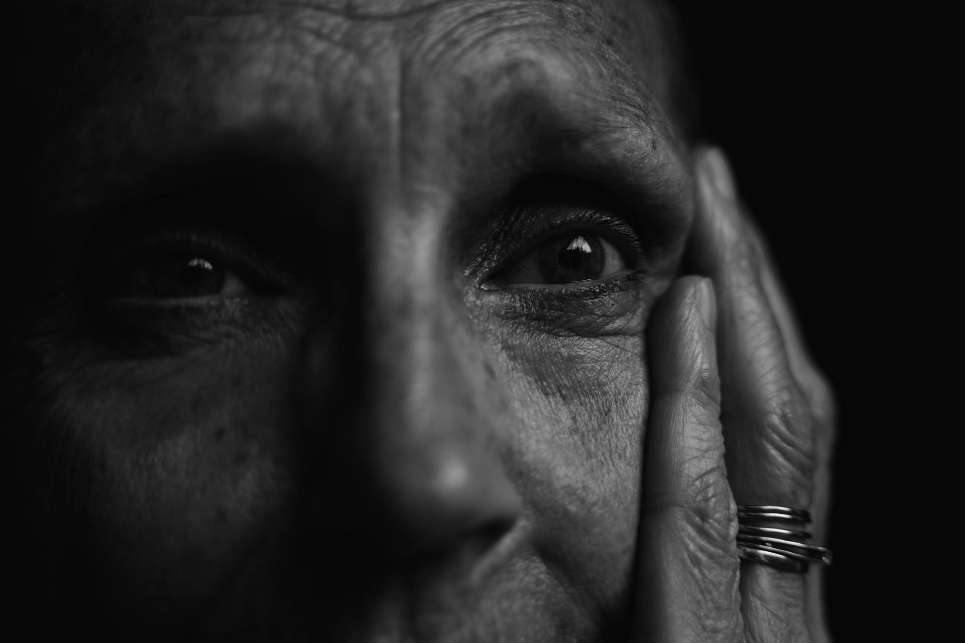 Grayscale shot of an emotional older person holding their face | Source: Pexels
