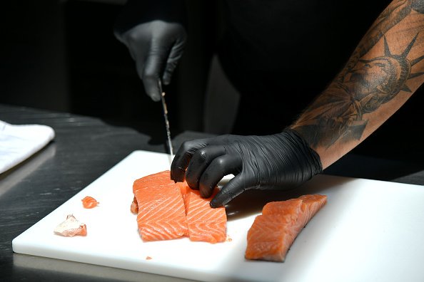Un homme qui découpe du poisson.| Photo : Getty image