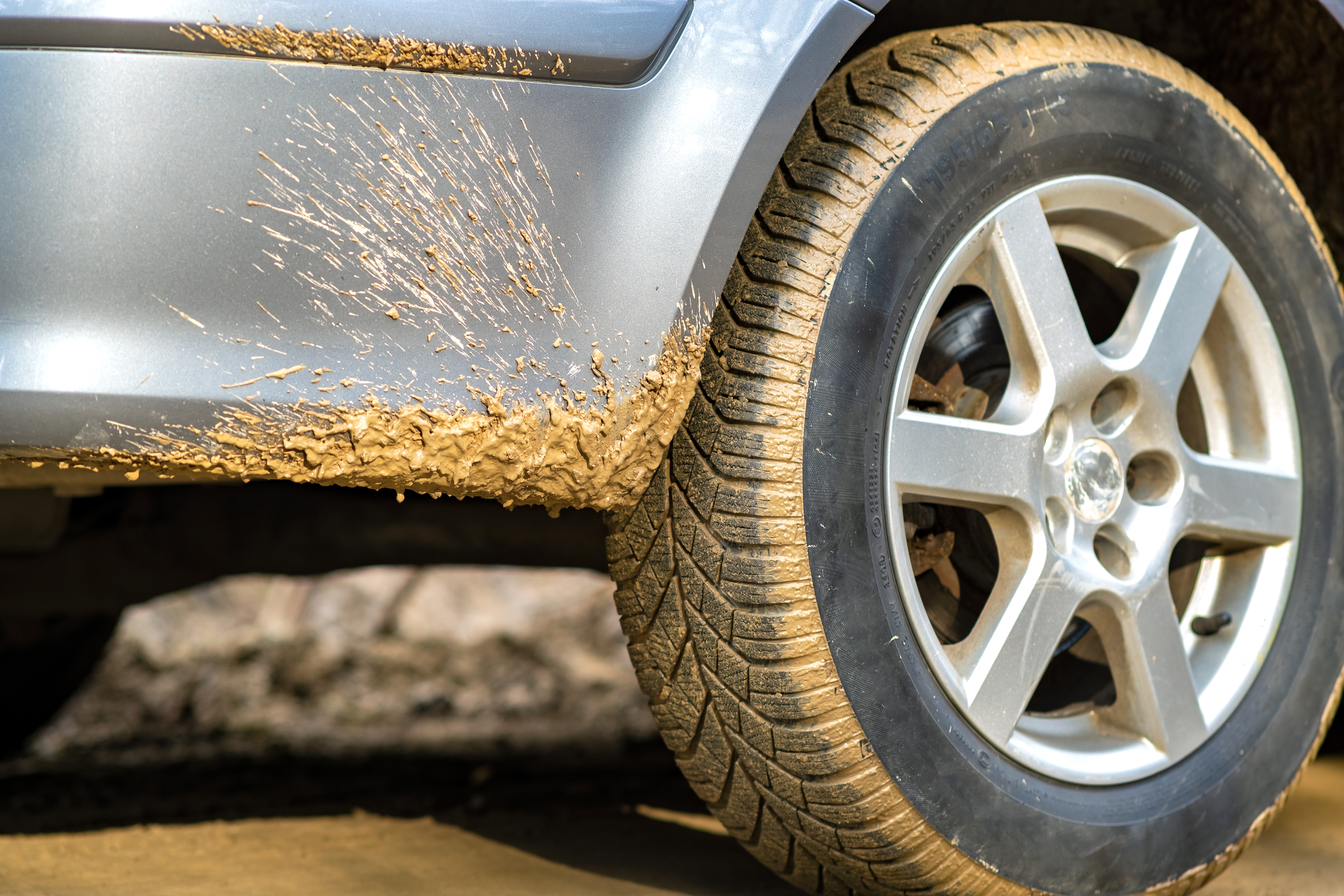 Close up of dirty car wheel with rubber tire covered with yellow mud. | Source: Shutterstock