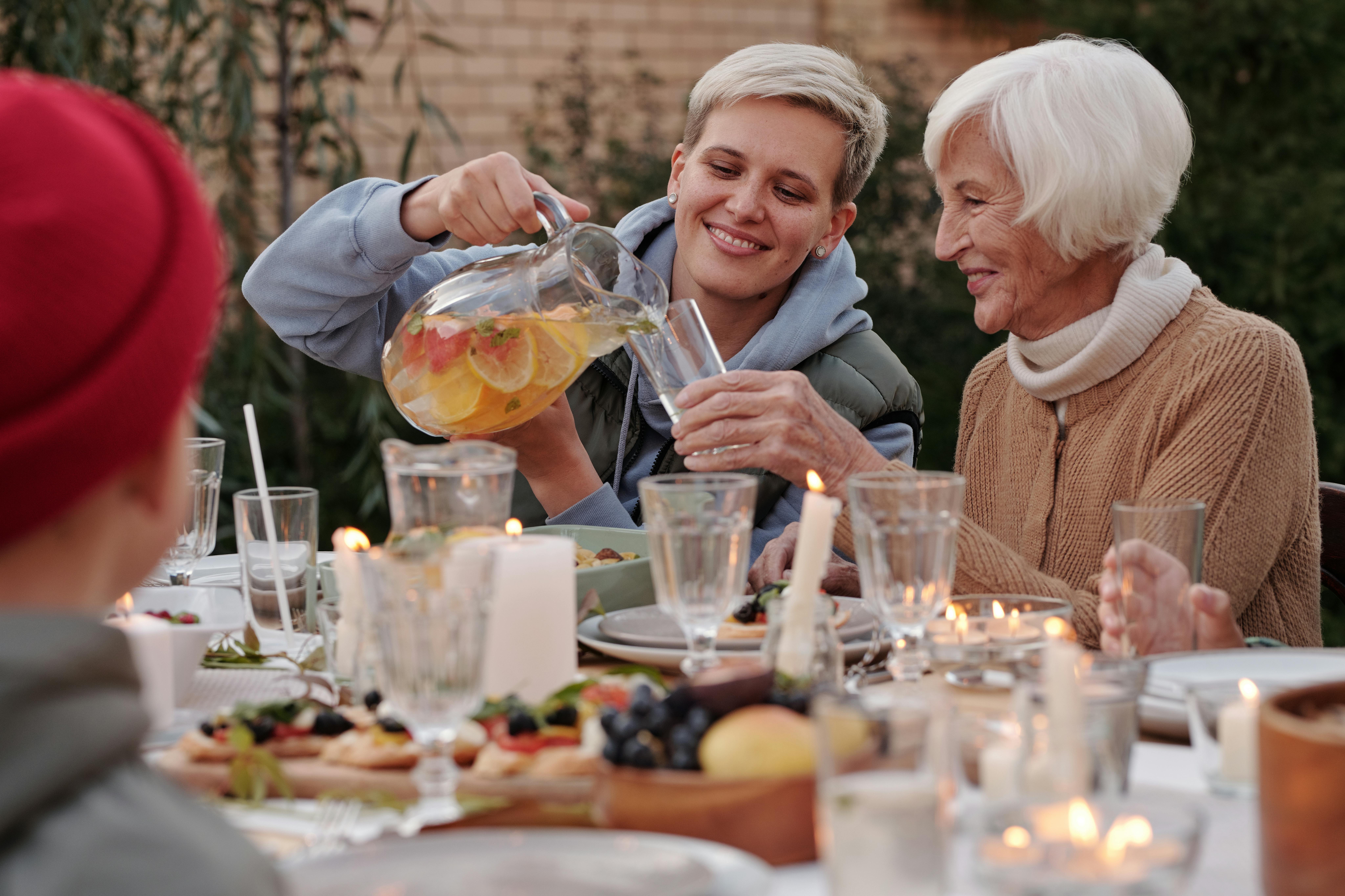 A cheerful young woman filling an older woman's glass with punch as they both smile | Source: Pexels
