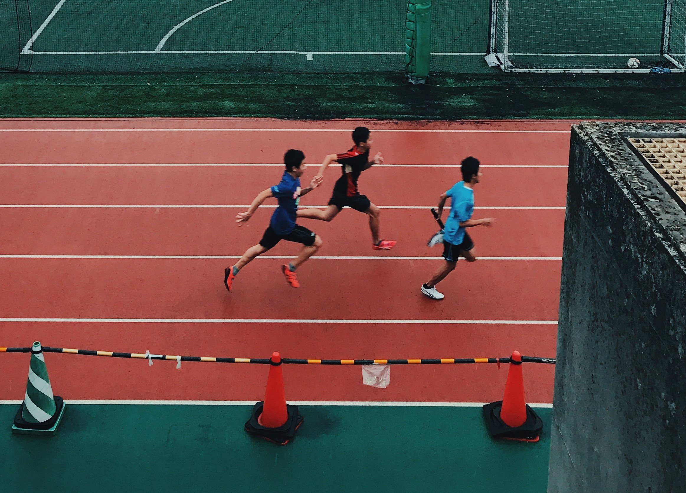 Tres chicos corriendo en una pista de atletismo. | Foto: Unsplash