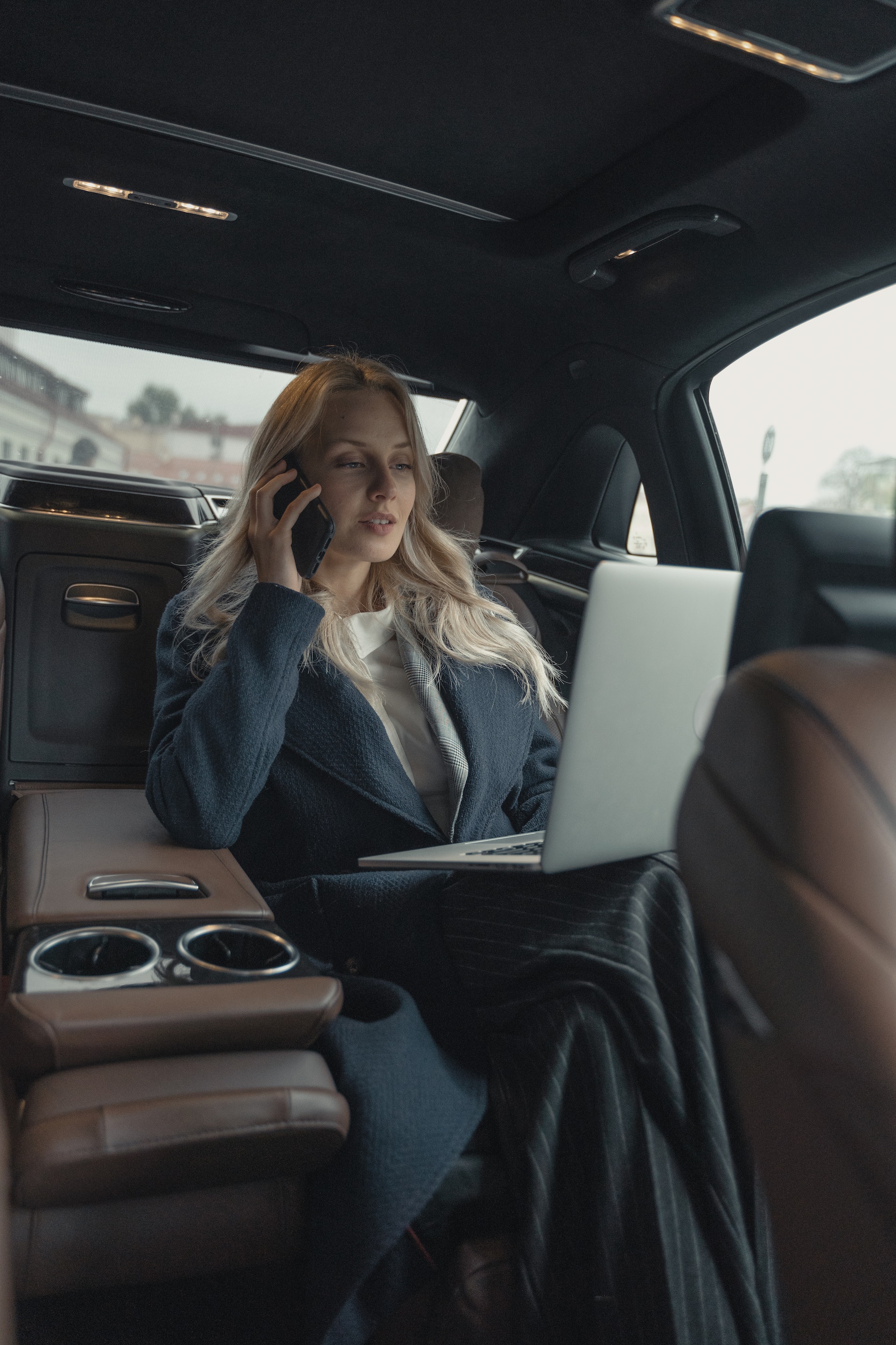 A woman working on a laptop in a car | Source: Pexels
