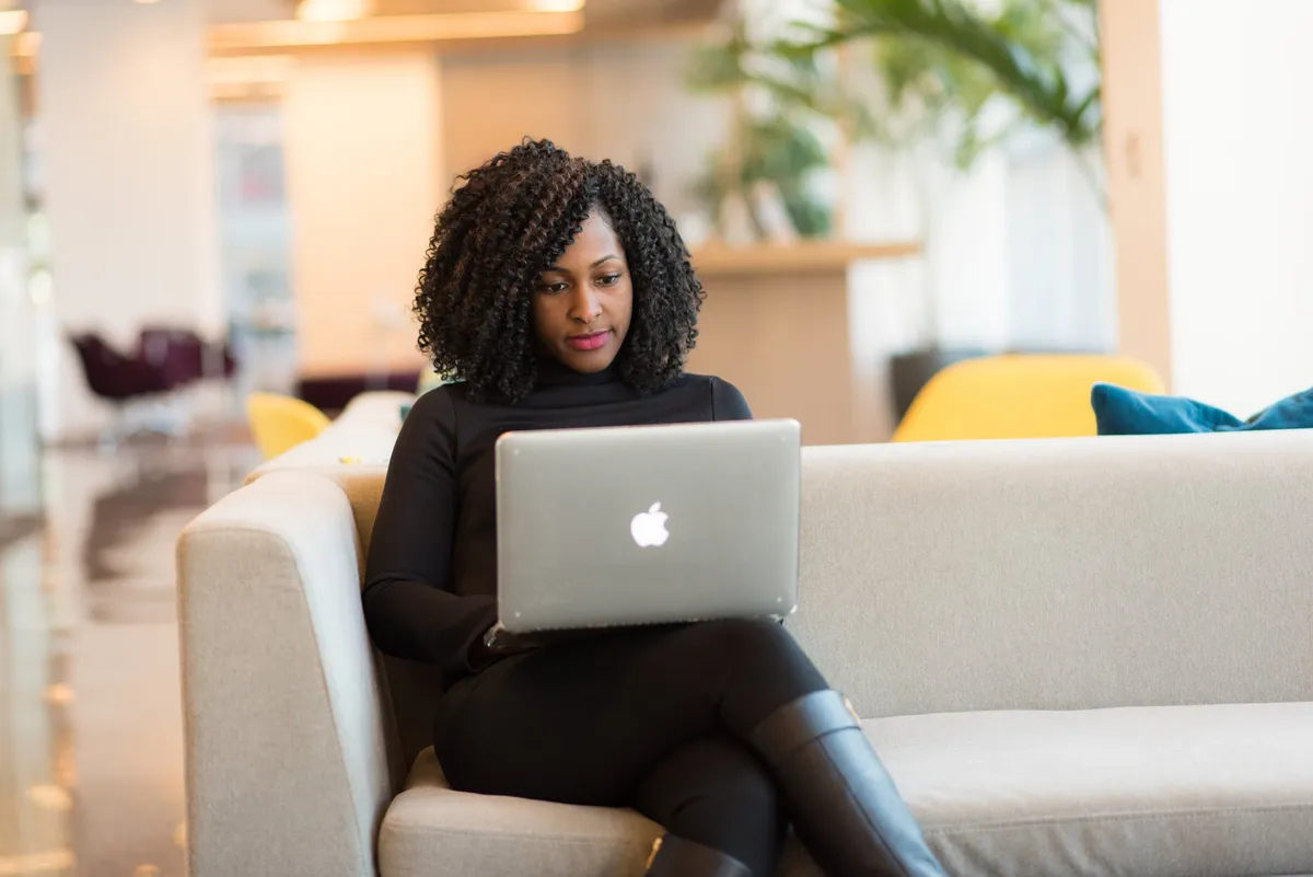 Femme assise sur un canapé et utilisant son ordinateur portable | Source : Pexels
