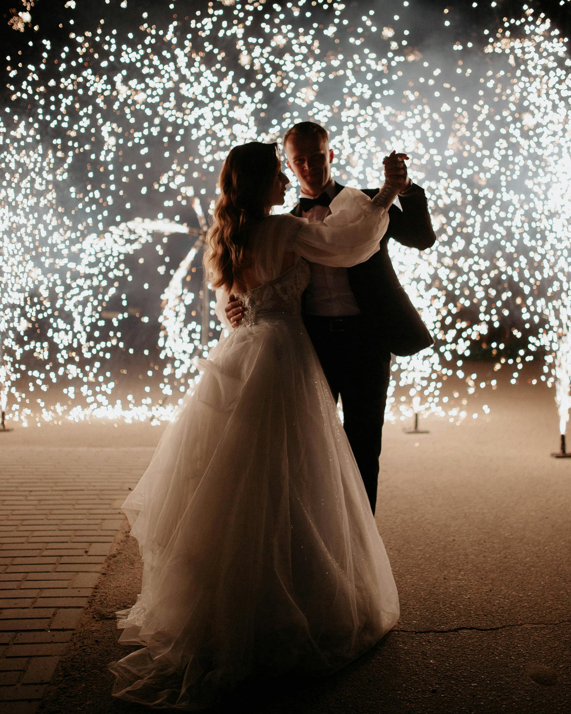 A bride and groom dancing with fireworks in the dark | Source: Pexels