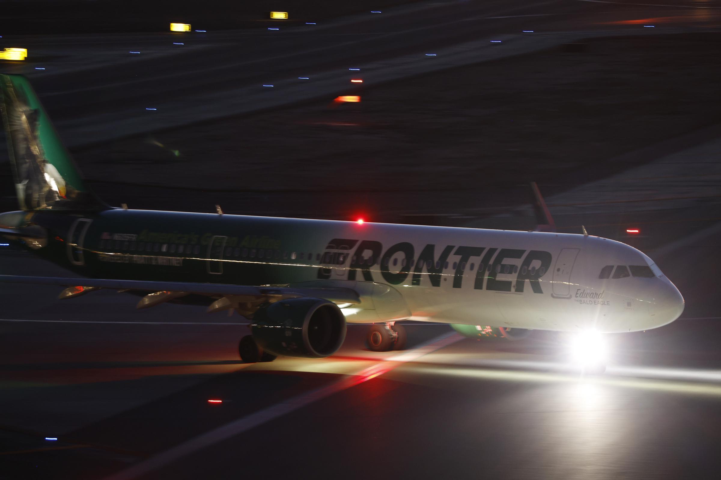 A Frontier Airlines plane prepares for departure on a runway at night | Source: Getty Images