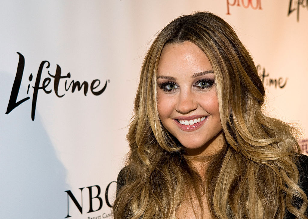 Glowing in smoky eye makeup and loose curls, Amanda Bynes strikes a confident pose at the "Living Proof" premiere in Washington D.C., dressed in a classic black ensemble.