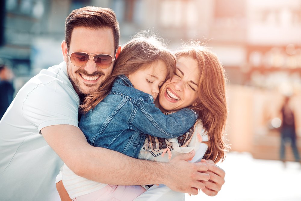 Pareja abrazando a su hija. | Foto: Shutterstock