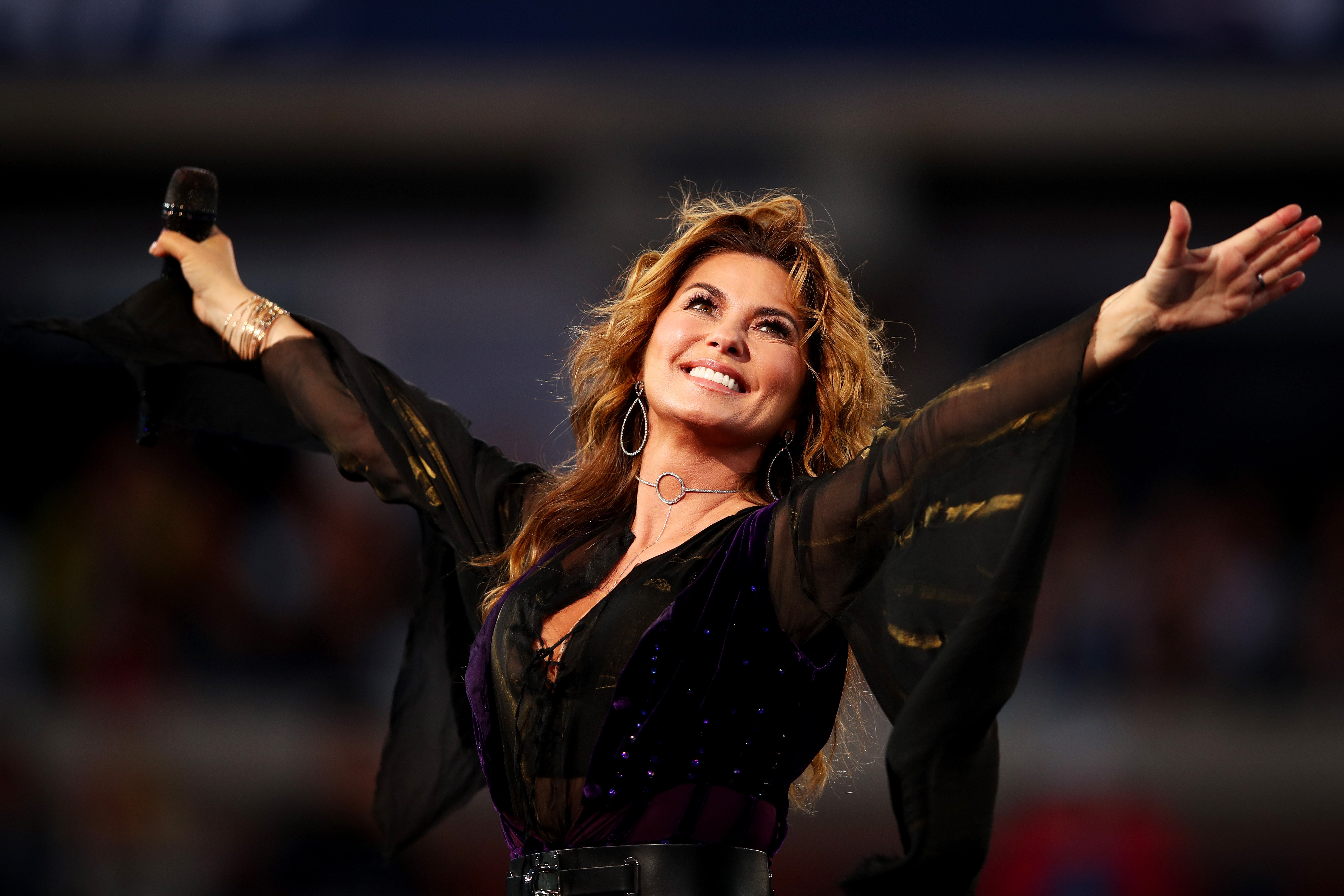 Taking the stage for the 2017 US Open opening ceremony, a beaming Shania Twain paired dramatic, sheer bell sleeves with a structured dark vest and silver hoop earrings. | Source: Getty Images