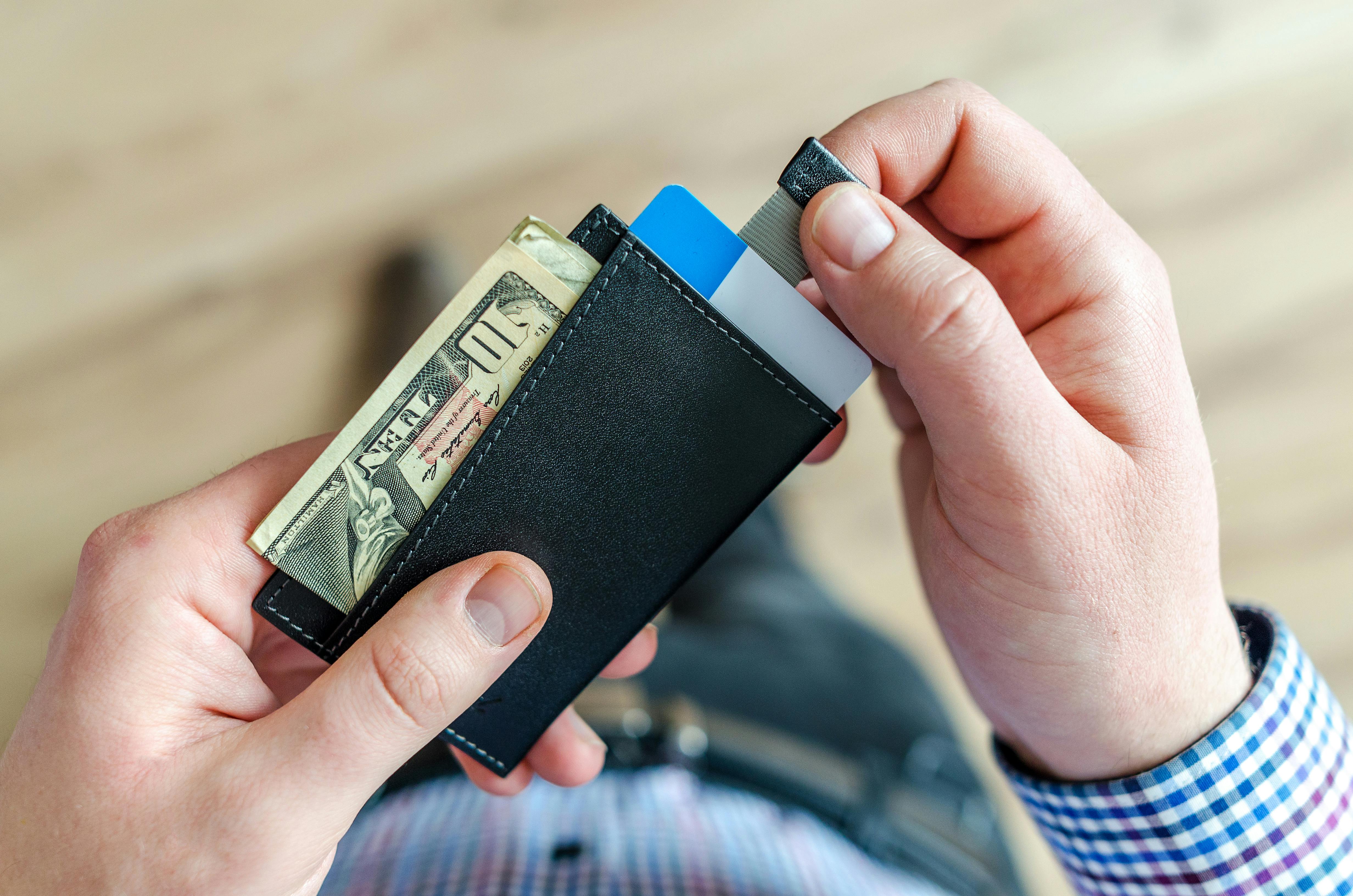 A man holding a wallet with bank cards and money | Source: Pexels