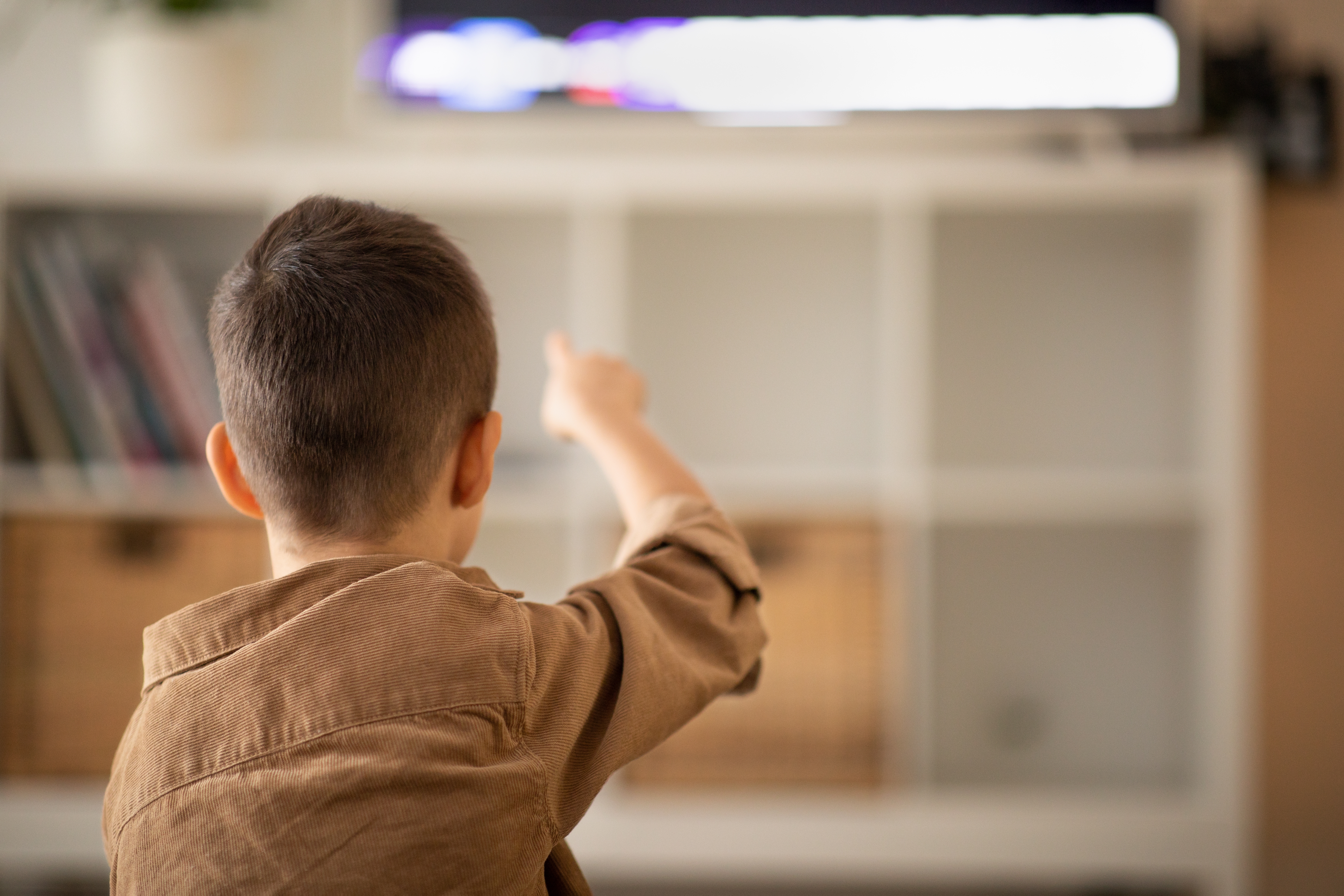 Small kid watch video, pointing finger at tv set. | Source: Shutterstock