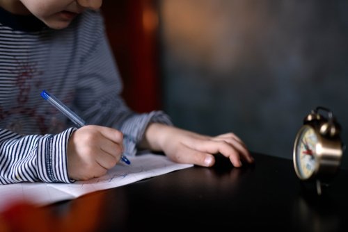 A boy writing a note. | Source: Shutterstock.