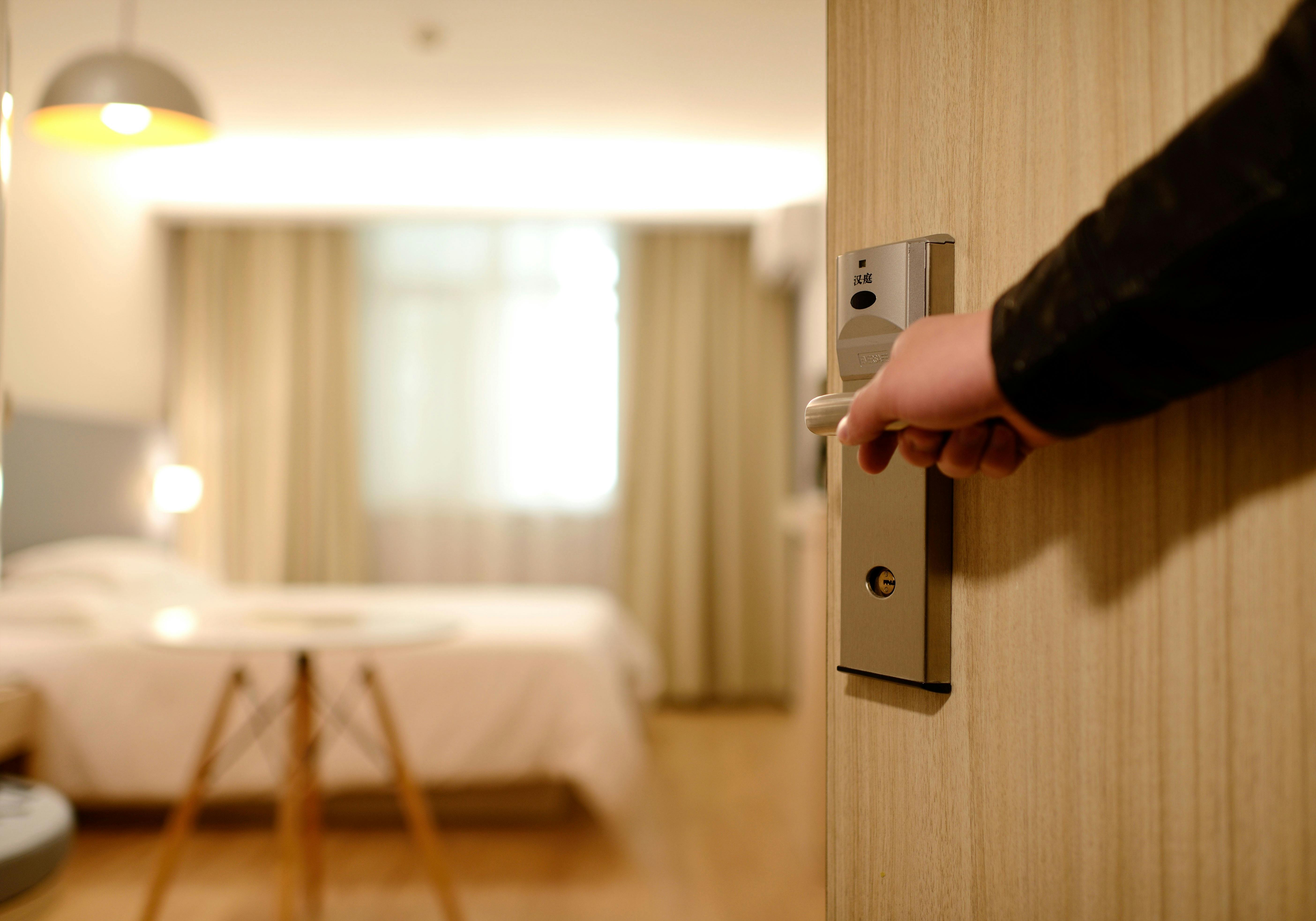 Una persona que mantiene abierta la puerta de una habitación de hotel | Fuente: Pexels