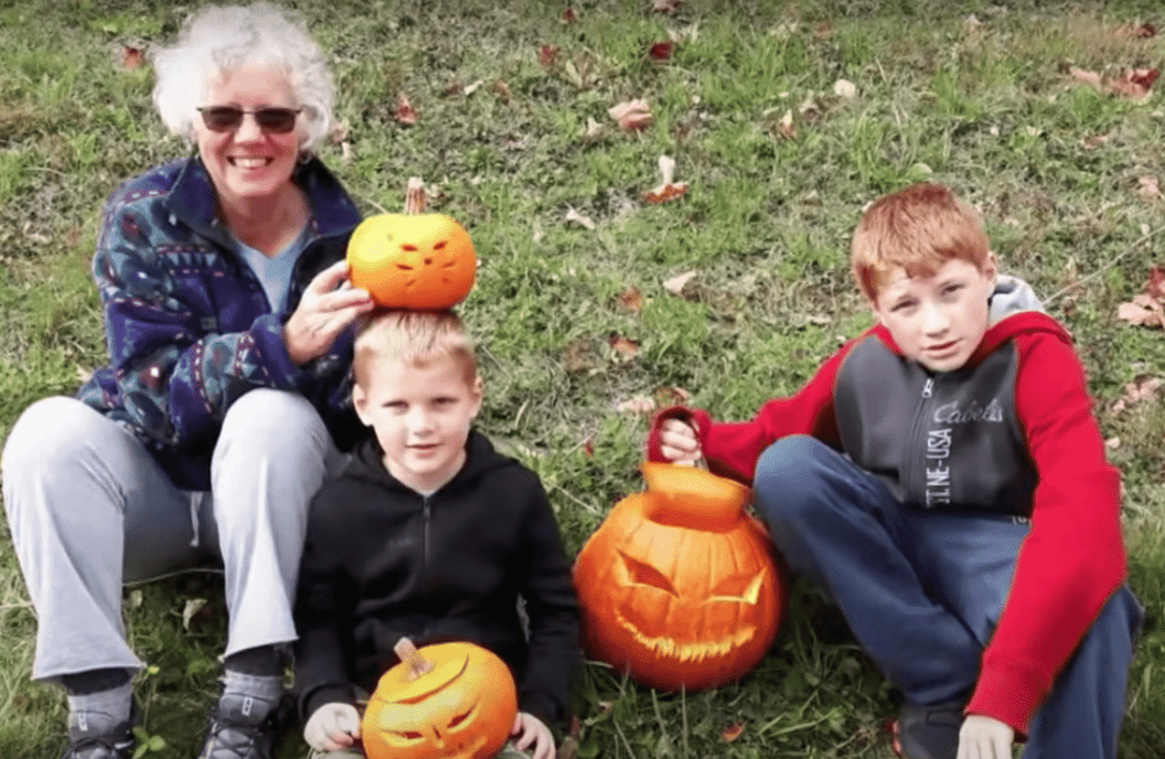Une grand-mère qui a été expulsée d'un avion est assise sur l'herbe avec ses deux petits-enfants | Photo : Youtube/Inside Edition