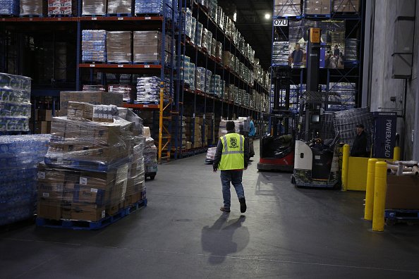 A worker walks past pallets of boxes at a Kroger Co. grocery distribution center in Louisville, Kentucky, U.S., on Friday, March 20, 2020. | Photo: Getty Images