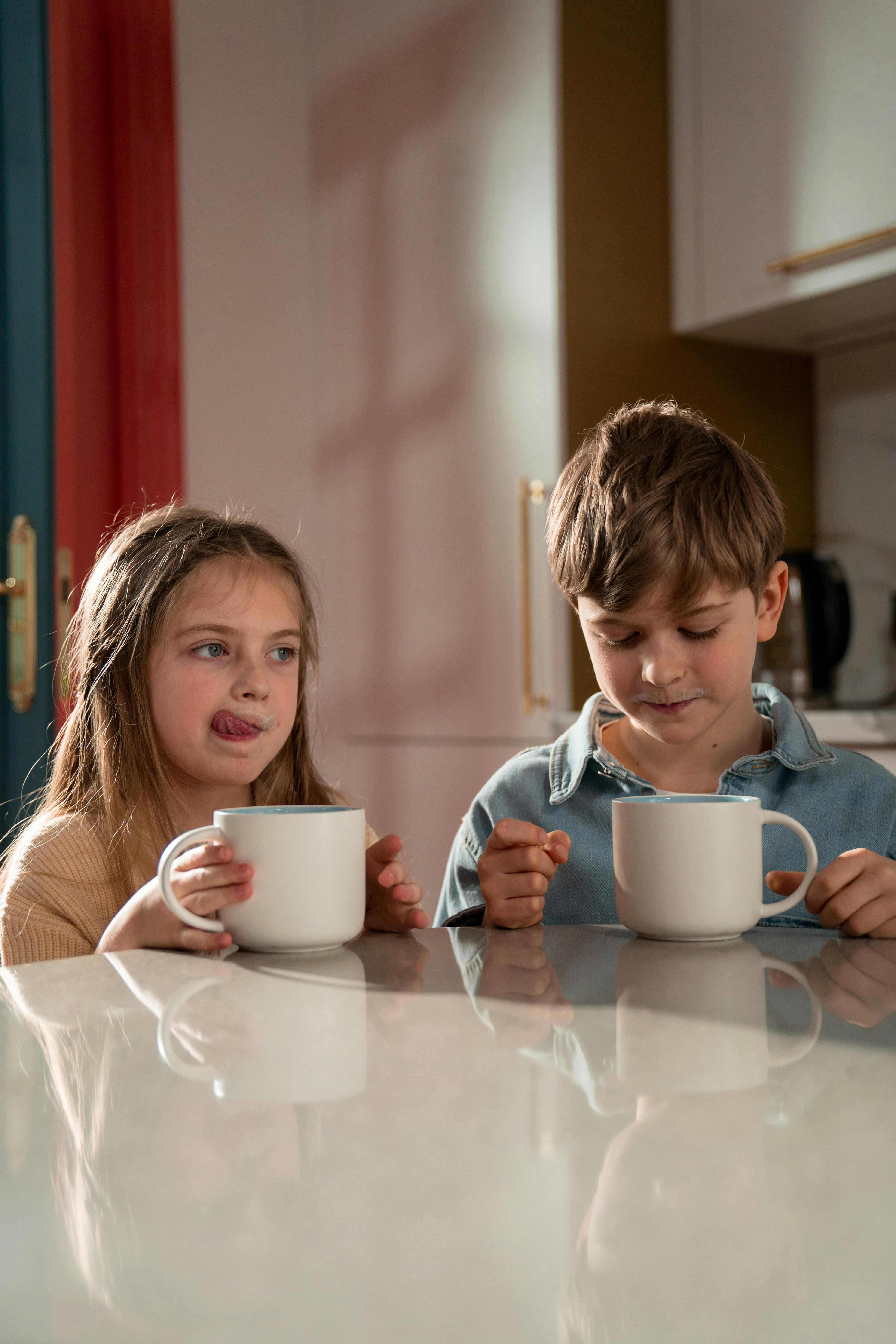 Two kids sitting at table and enjoying their drinks | Source: Pexels