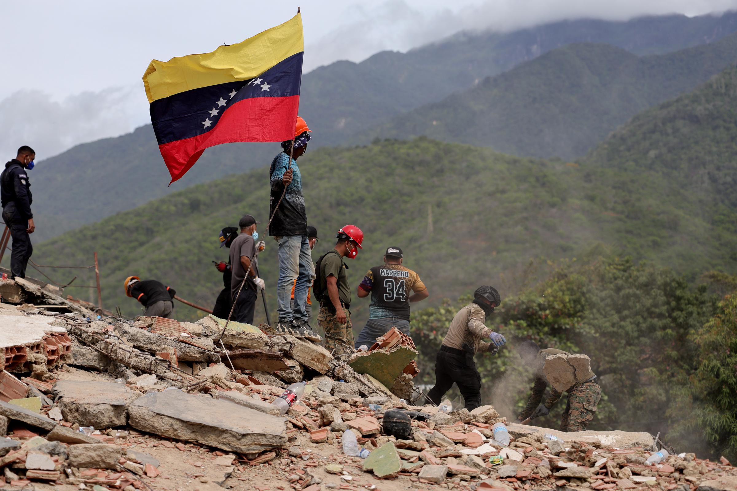 Rescue workers continue searching through the rubble as a Venezuelan flag flies above the disaster site in Caraballeda. Emergency crews remained at the scene for days as recovery efforts continued. | Source: Getty Images