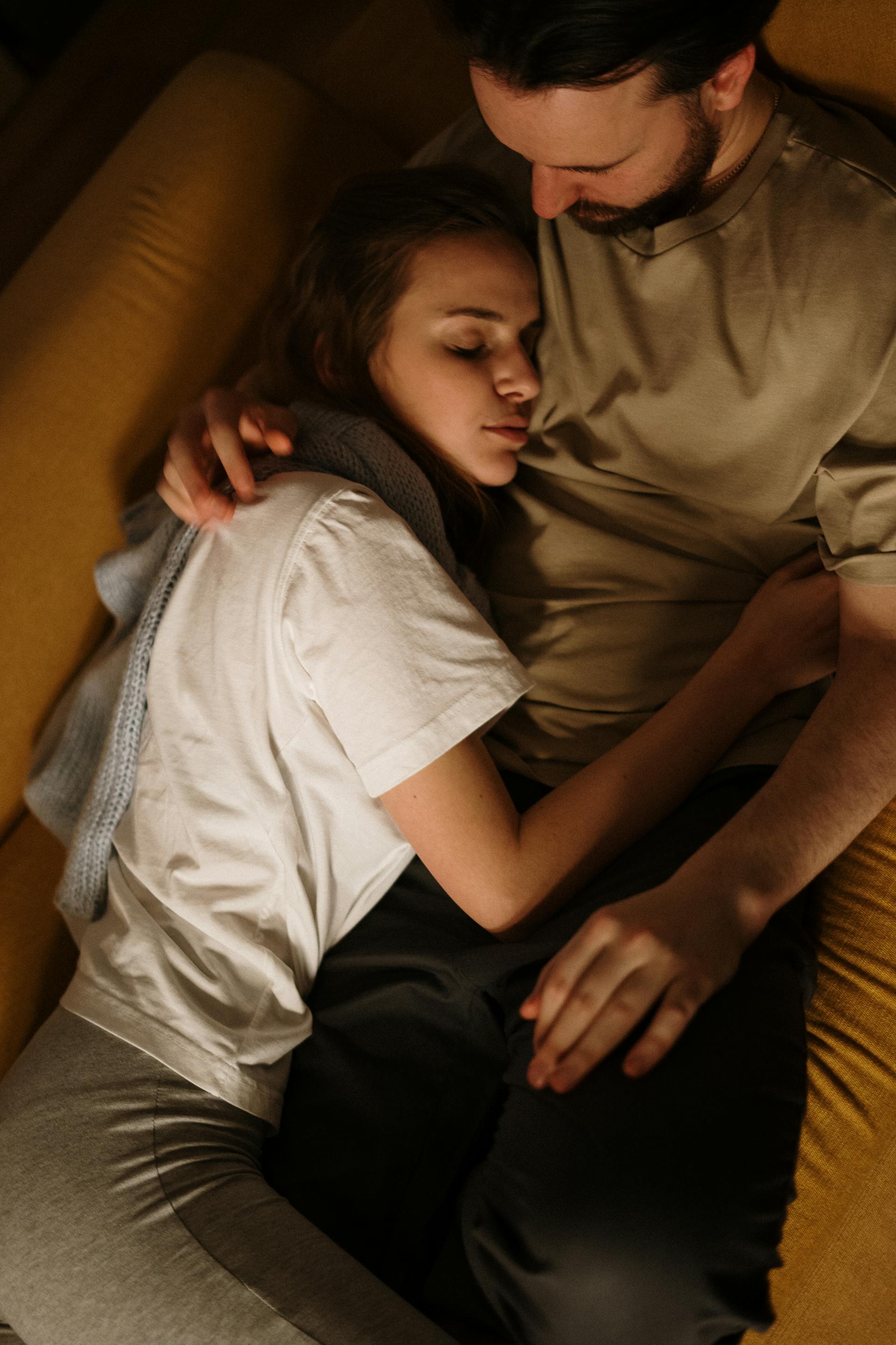 A man looking at his sleeping wife while they lie together on a couch | Source: Pexels