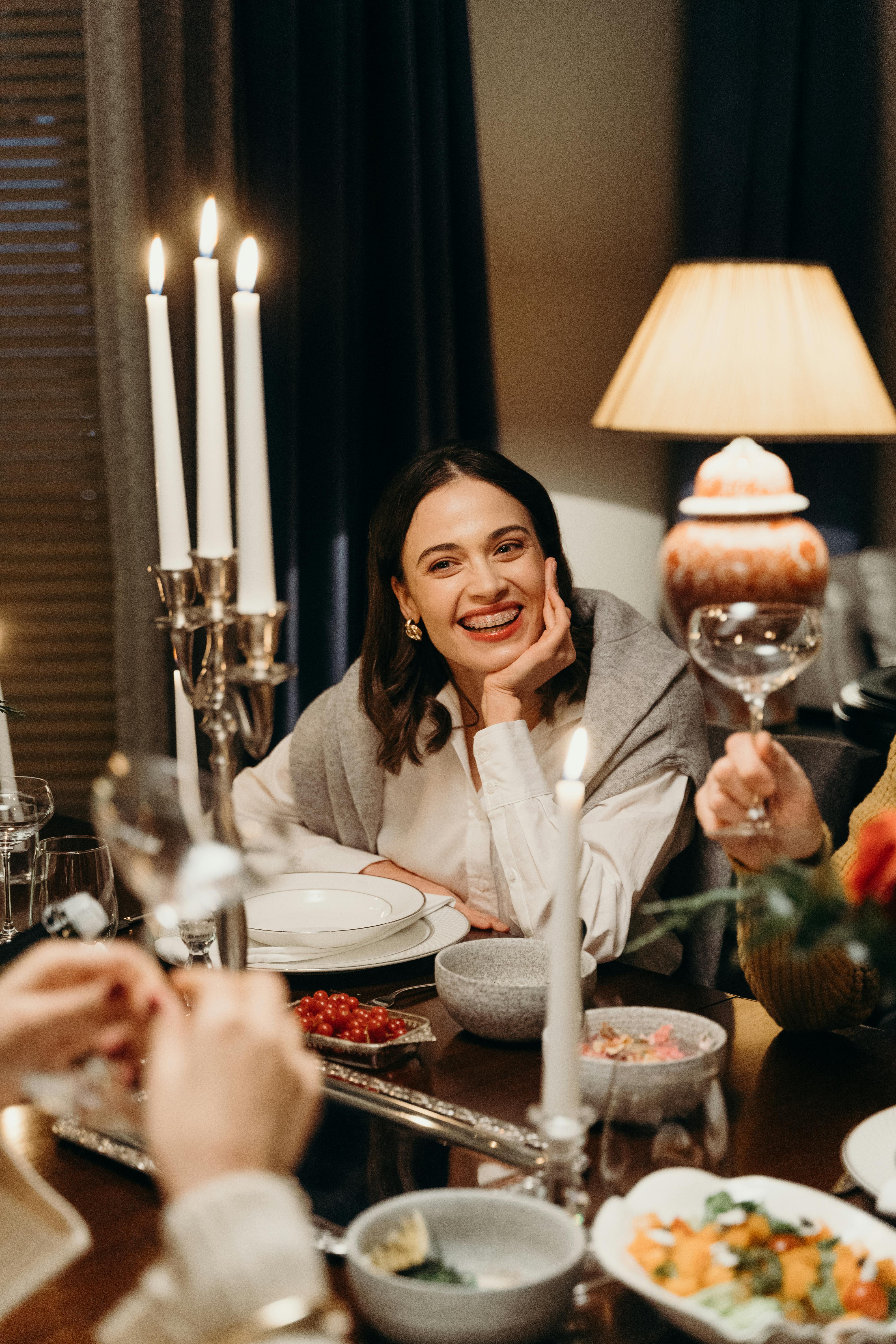 A smiling woman at the dinner table | Source: Pexels