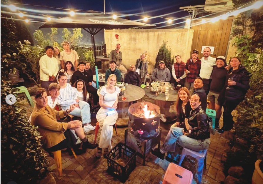 A large group gathers outdoors at night around a glowing fire pit at Jack Quaid and Claudia Doumit’s wedding. | Source: Instagram/smokey_horse