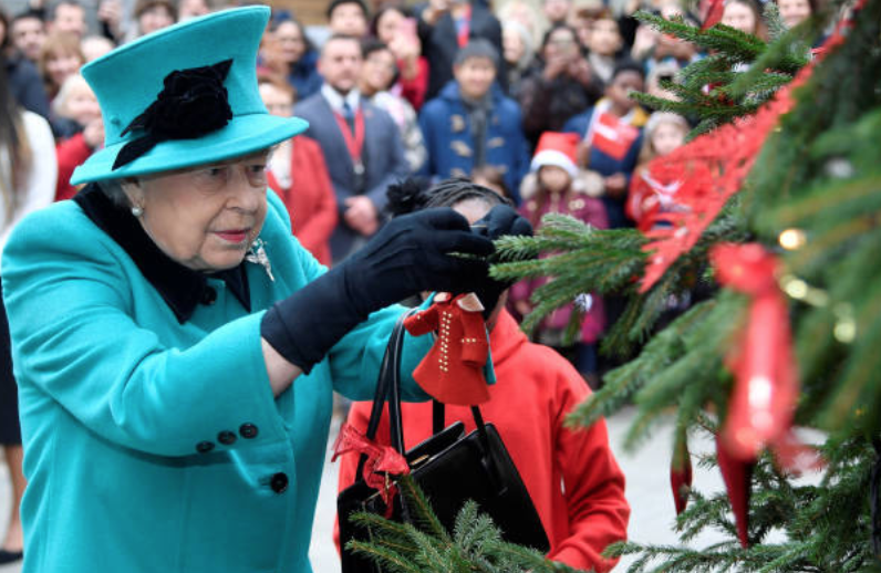 Queen Elizabeth attaches an ornament to a Christmas tree during the opening of the Queen Elizabeth II centre at CORAM, on December 05, 2018 in London, England | Source: Toby Melville - WPA Pool/Getty Images