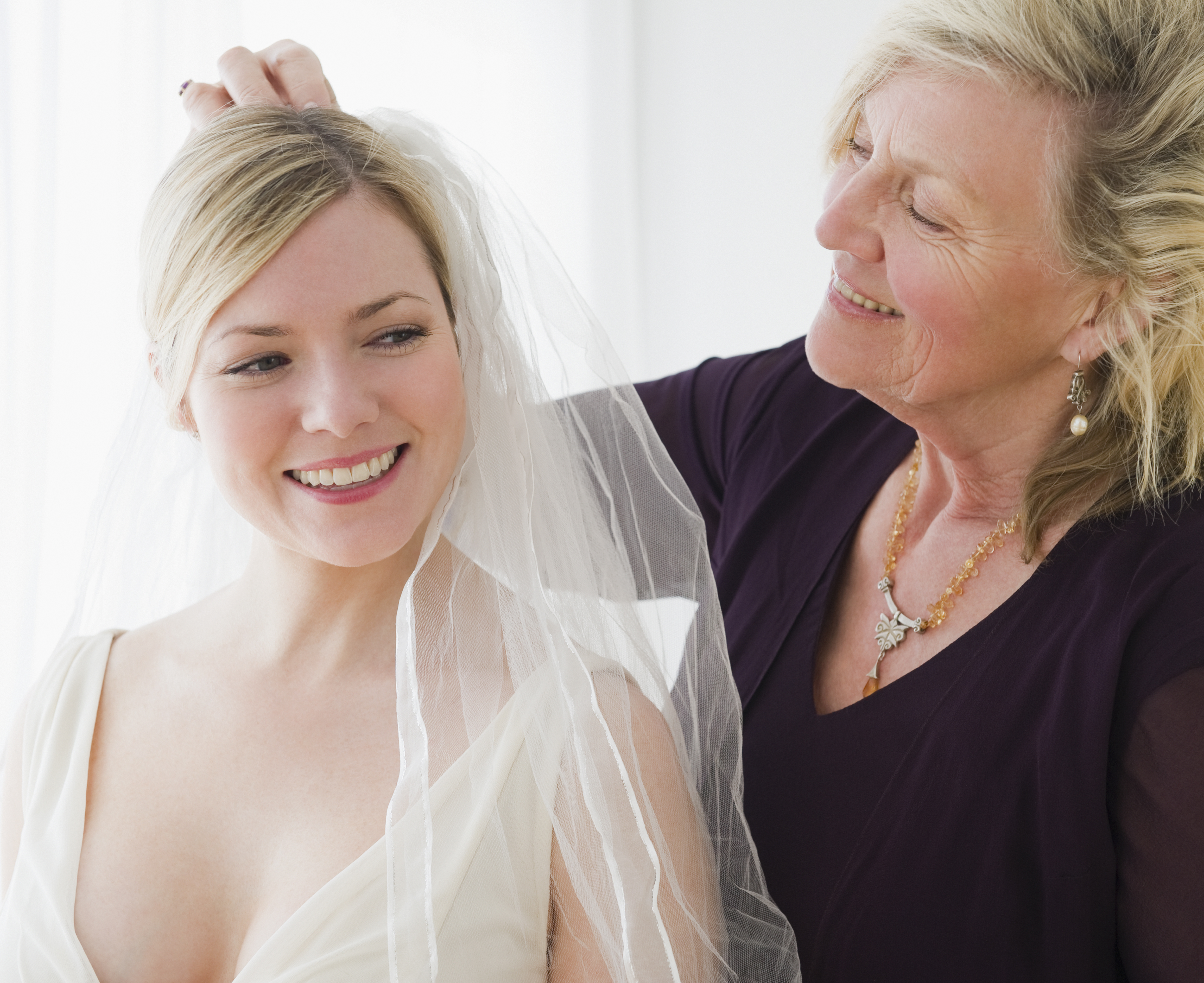 An older woman helping a younger woman try on a wedding dress | Source: Getty Images