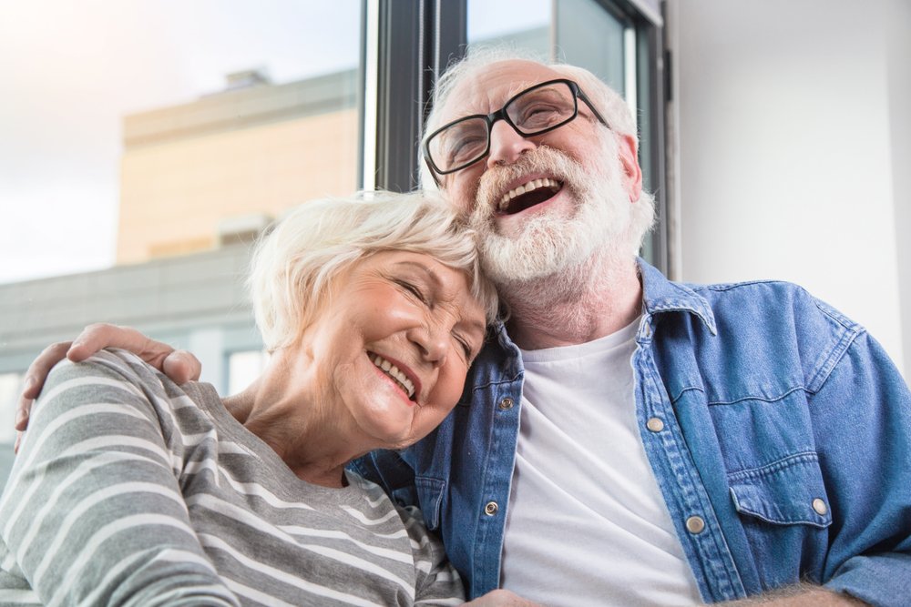 A waist up portrait of an old happy man and woman sharing a joke together | Photo: Shutterstock/Olena Yakobchuk