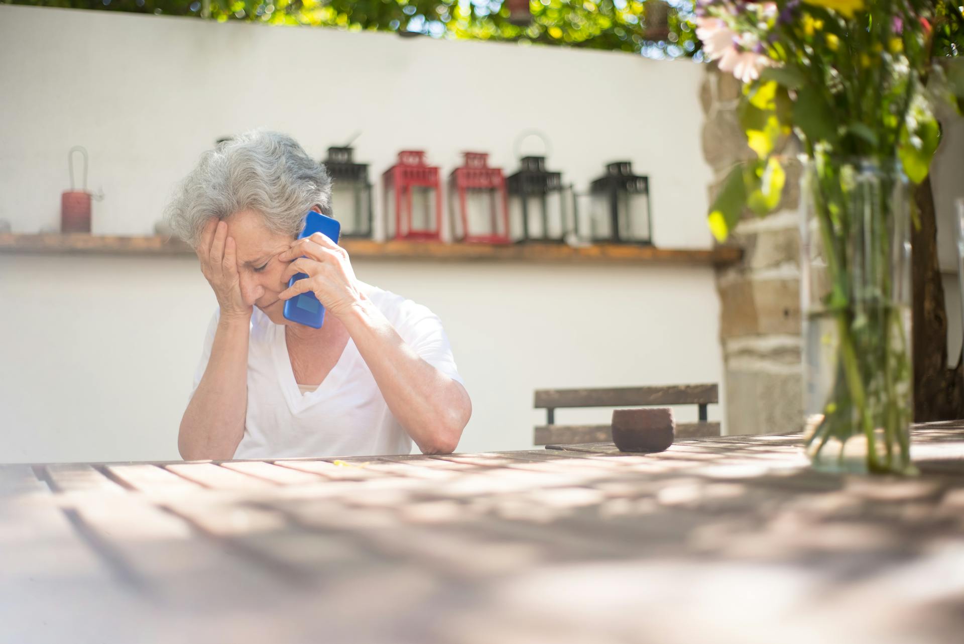 A sad elderly woman talking on the phone