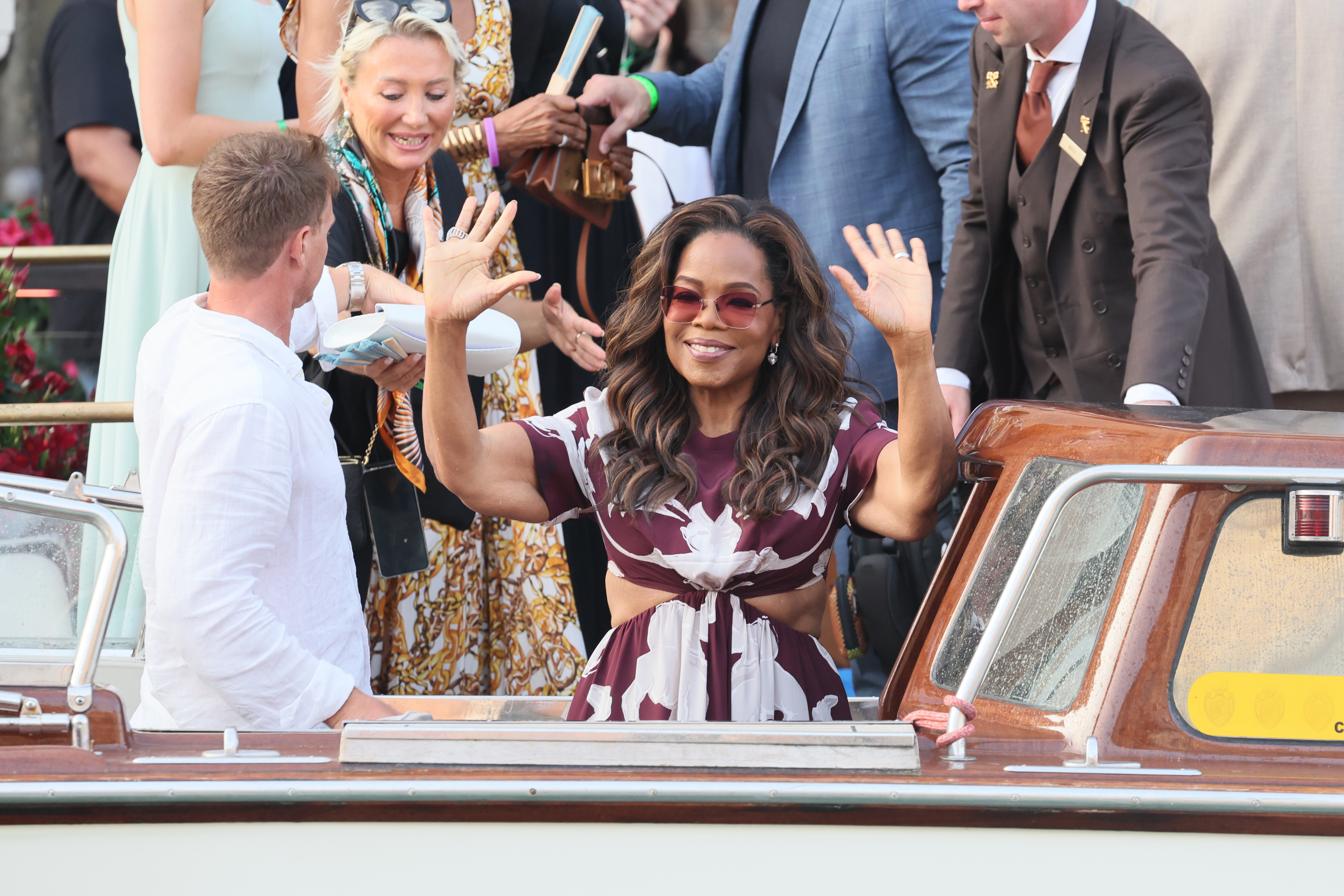 Oprah Winfrey smiles and waves at the crowd as she attends Jeff Bezos and Lauren Sanchez's wedding in Venice, Italy on June 26, 2025. The loose skin around her arms, that has the media buzzing, move with her movements.