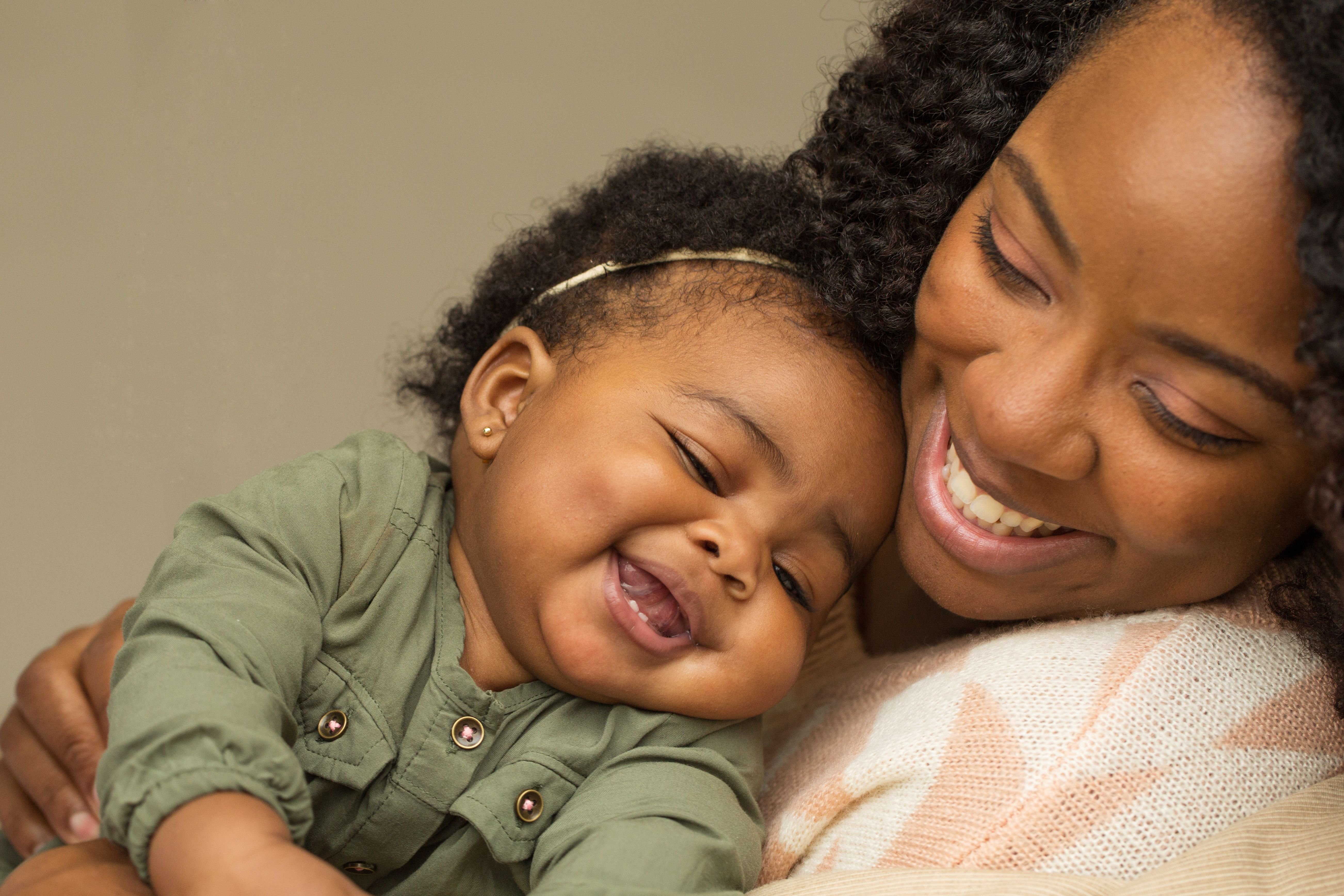 A woman and baby cuddling and smiling. │ Source: Shutterstock