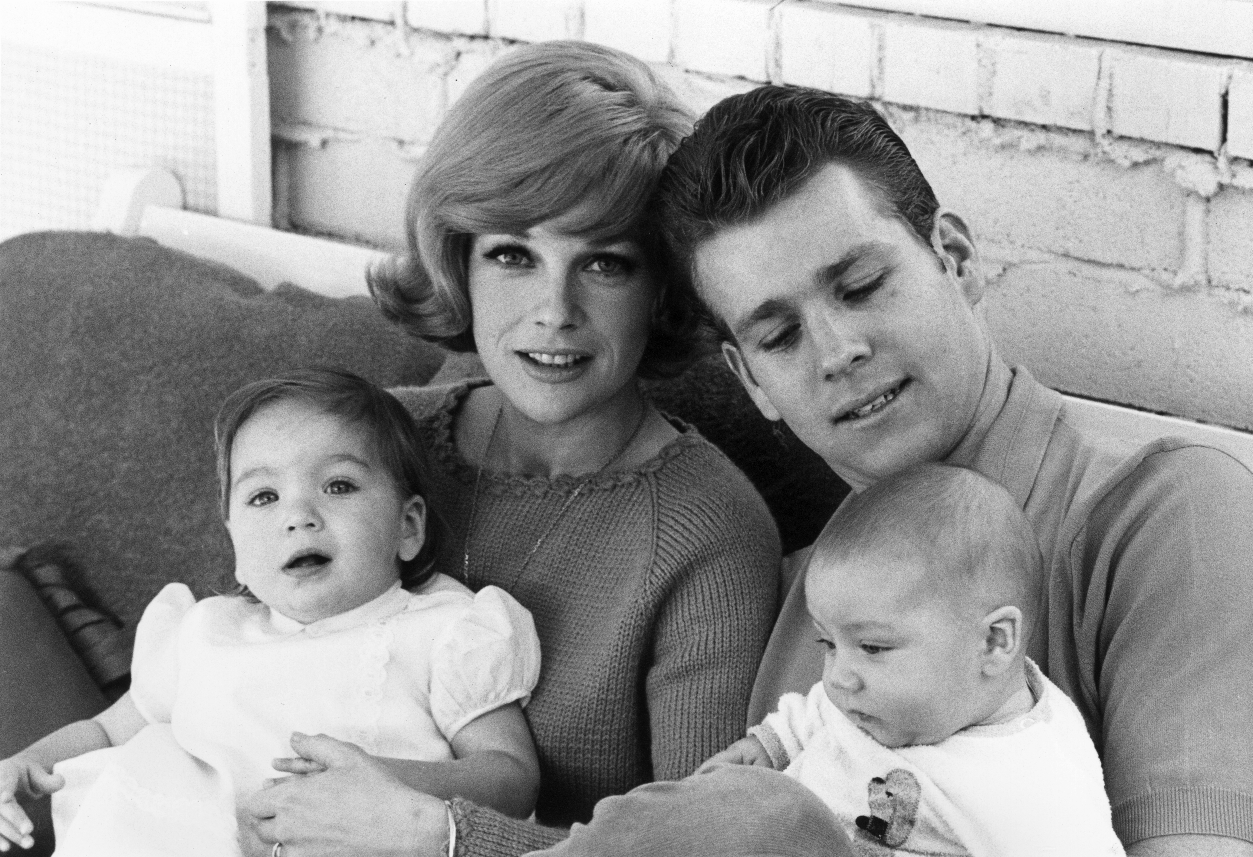 Ryan O'Neal seated with his son, Griffin, and Joanna Moore, who has their daughter, Tatum, on her lap, 1965.| Source: Getty Images