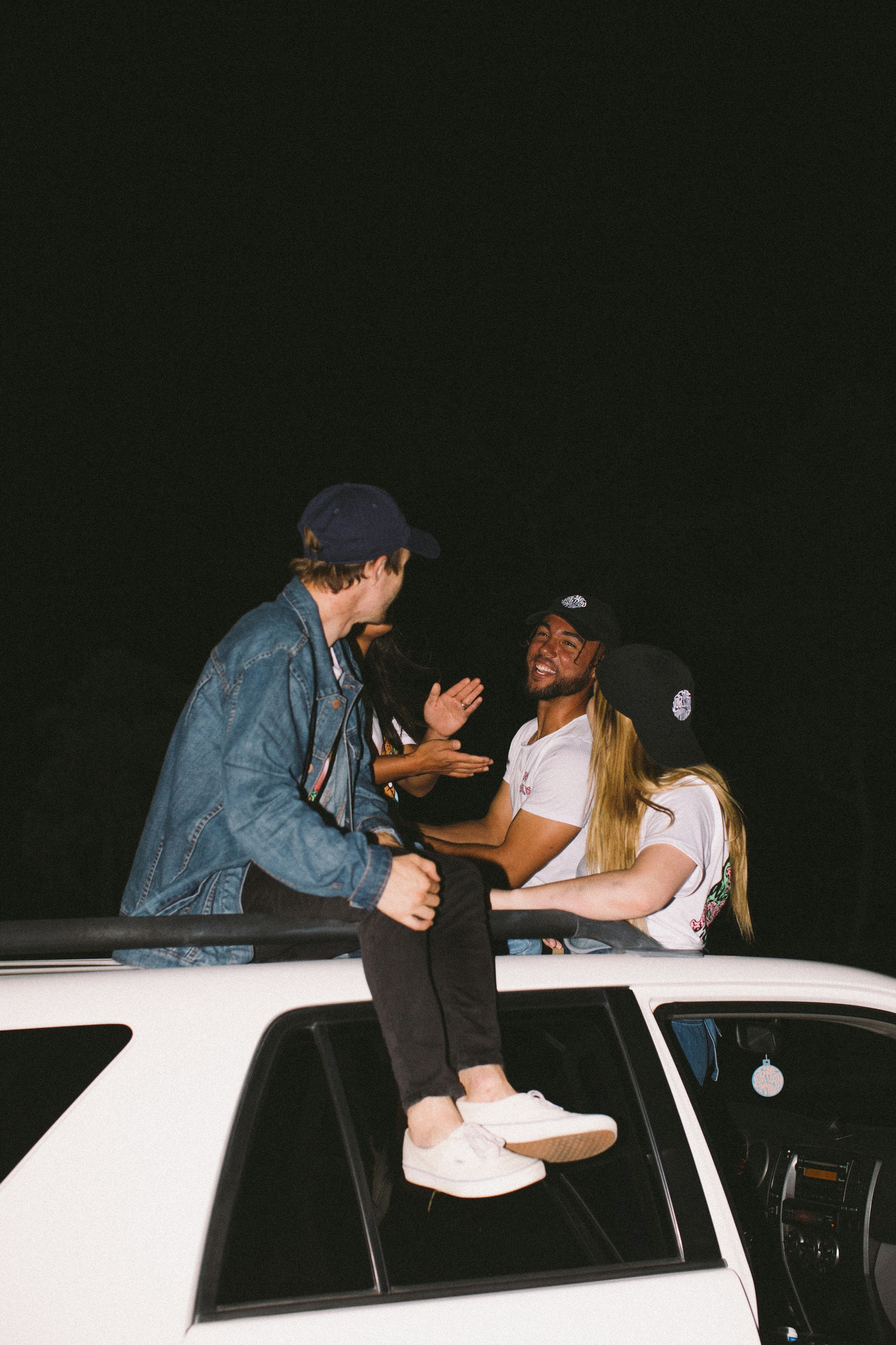 Four youngsters sitting on a vehicle roof | Source: Unsplash