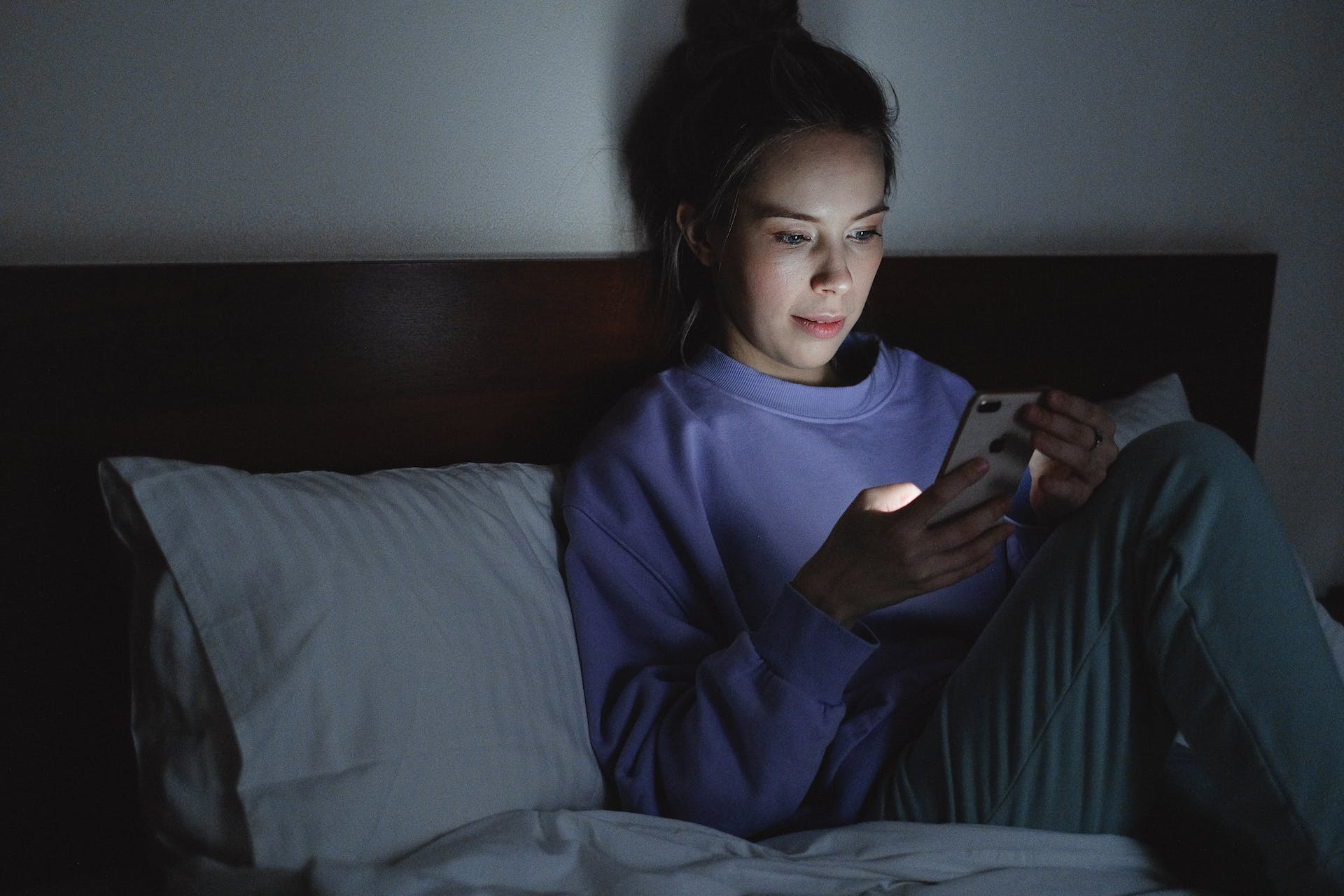 Woman using her phone while sitting on bed | Source: Pexels