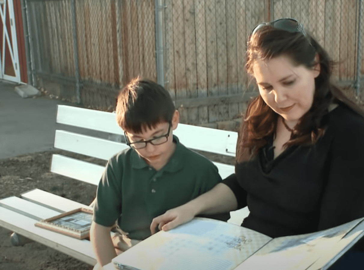 Julie Van Stone and her son look at photos of his deceased father | Photo: youtube.com/USA TODAY 
