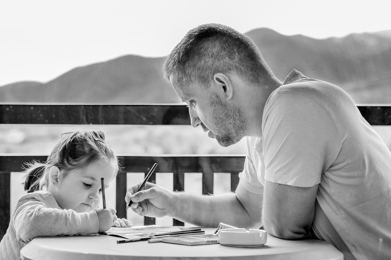 Man assisting a little girl with schoolwork | Source: Pixabay