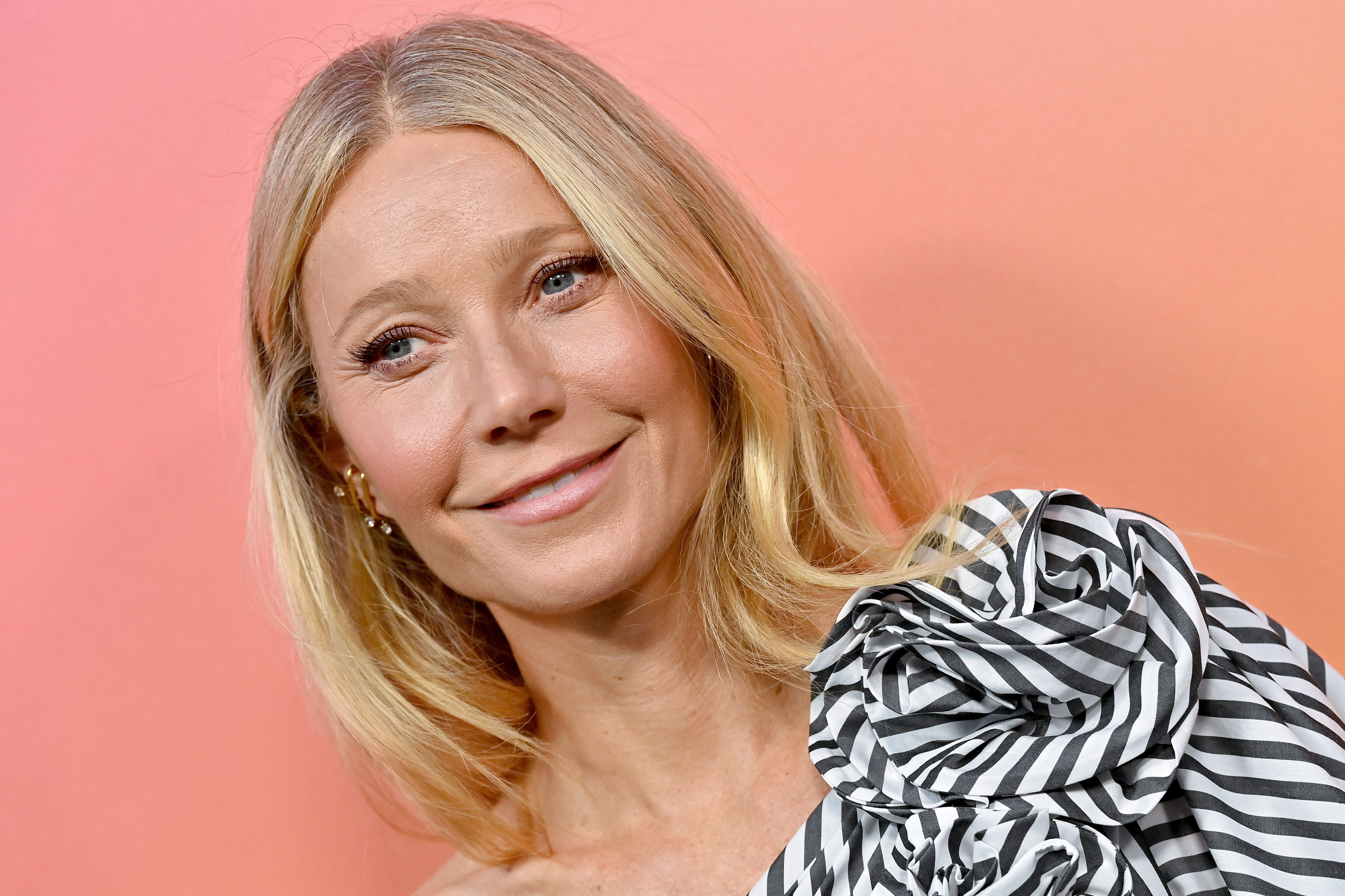 Gwyneth Paltrow attends an event in Beverly Hills on October 25, 2022, tilting her head gently while smiling, her hair worn straight and tucked behind her ear.