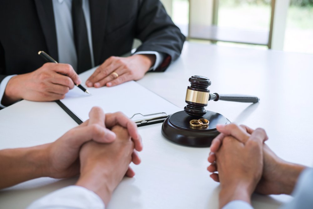 Pareja divorciándose mientras un abogado firma un acuerdo de divorcio. │Foto: Shutterstock