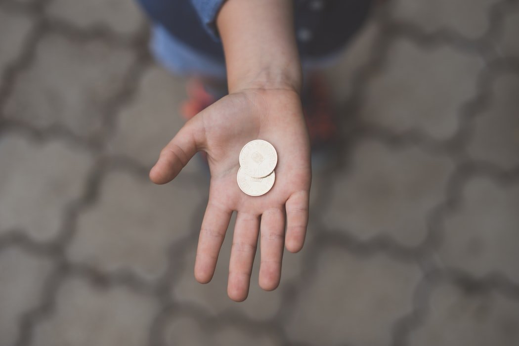 Niña sosteniendo dos monedas en su mano. | Foto: Unsplash