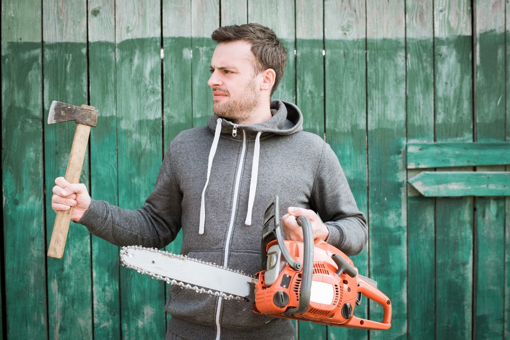 A man working at the lumberyard with chainsaw and ax. | Photo: Shutterstock.