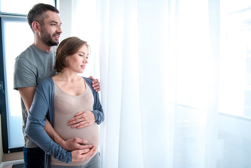 Soon-to-be parents looking over the window with joy and affection. | Photo: Shutterstock.