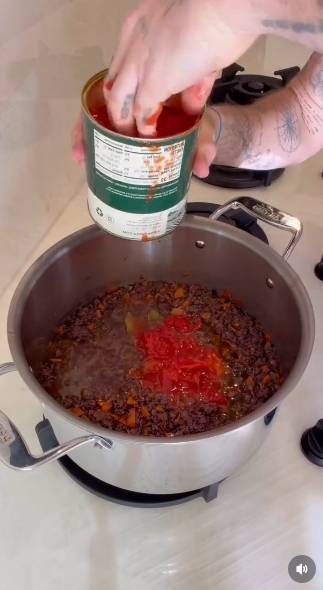 Brooklyn Beckham adds canned tomatoes to his homemade bolognese in a cooking video shared on January 30, 2026. | Source: Instagram/Brooklyn Peltz Beckham