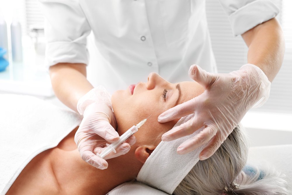 Mujer recostada recibiendo aplicación de bótox a un lado de su rostro. | Foto: Shutterstock