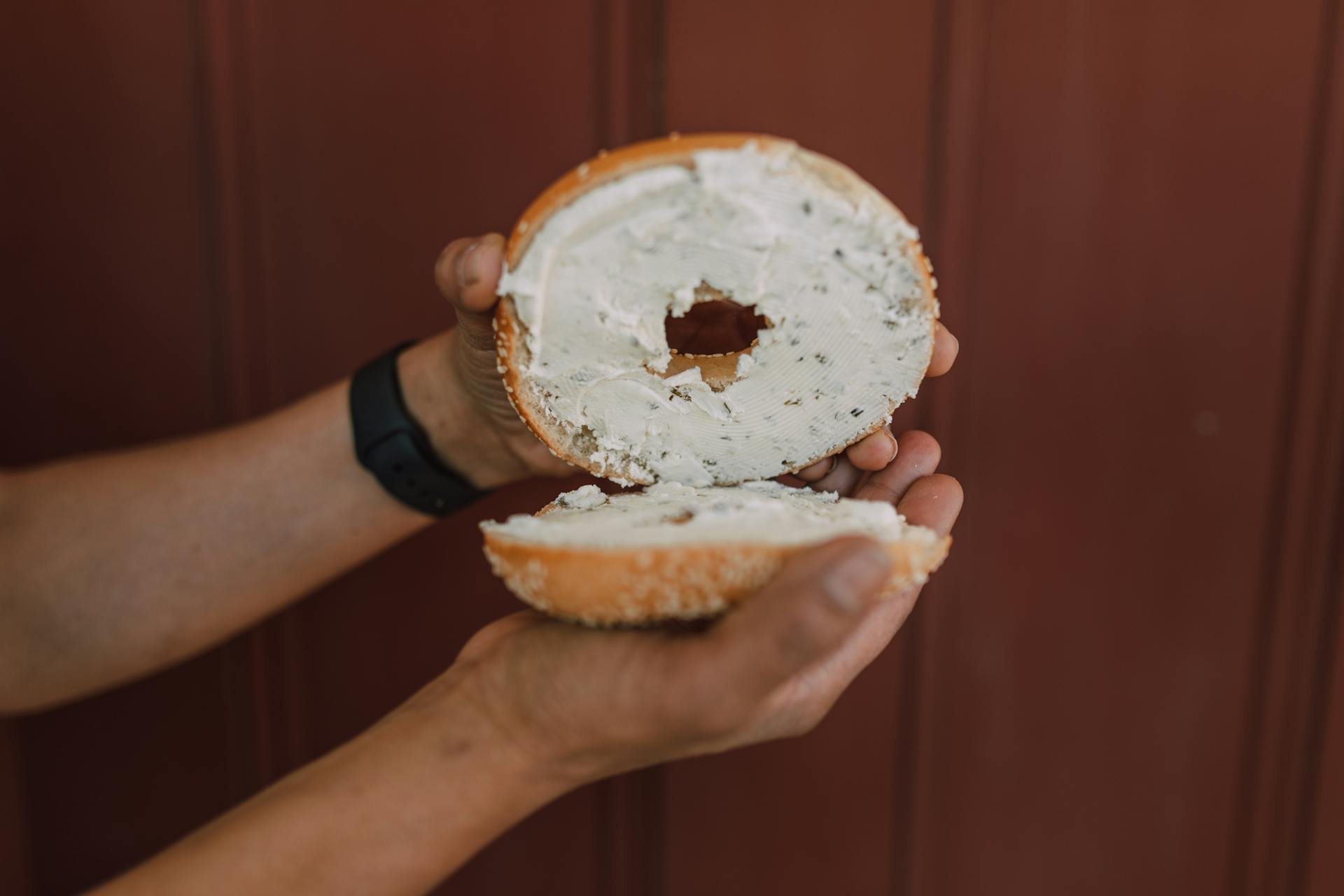A woman holding a bagel with cream cheese | Source: Pexels