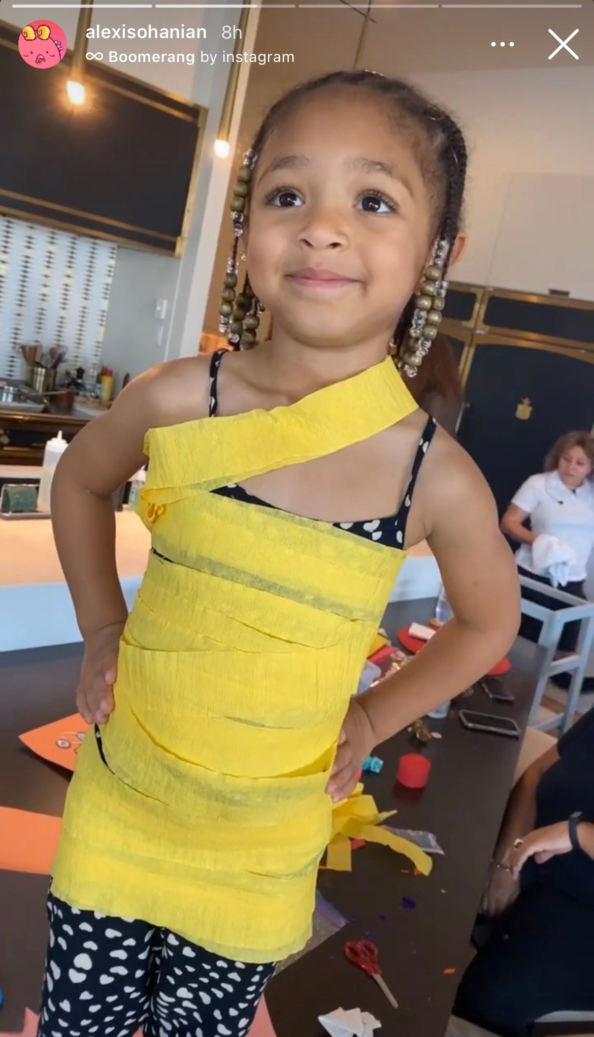 Serena Williams's daughter Olympia wrapped in yellow paper while wearing her black dress. | Photo: Instagram/Alexisohanian