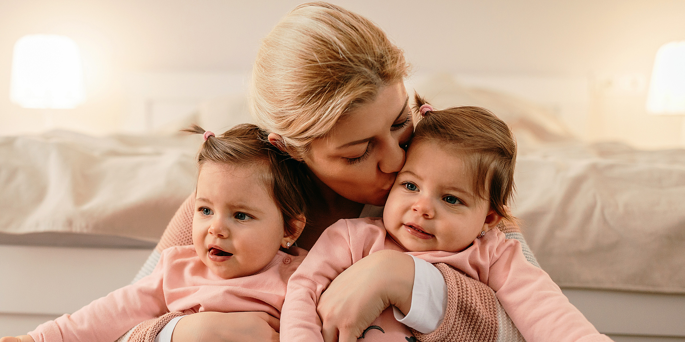 A woman holding her twin daughters | Source: Shutterstock