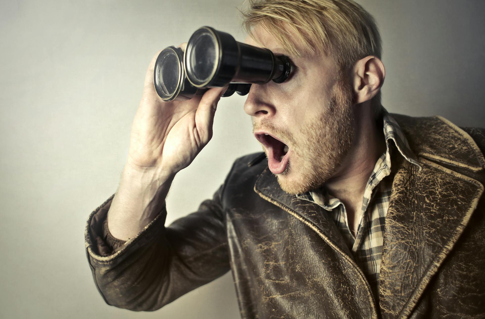 An extremely shocked man using binoculars to look at something | Source: Pexels