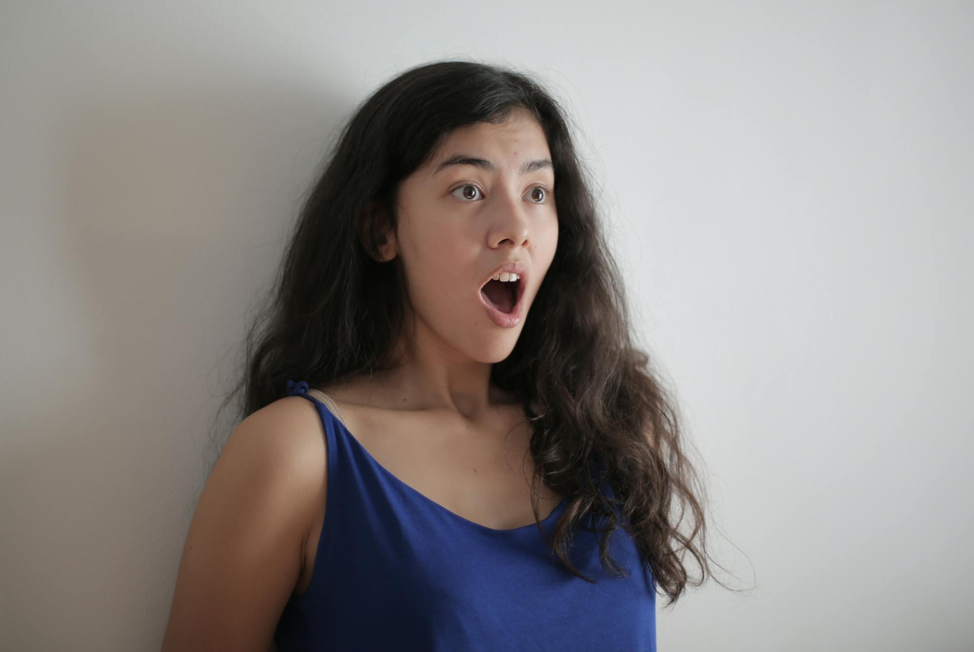 A shocked woman standing against a wall | Source: Pexels