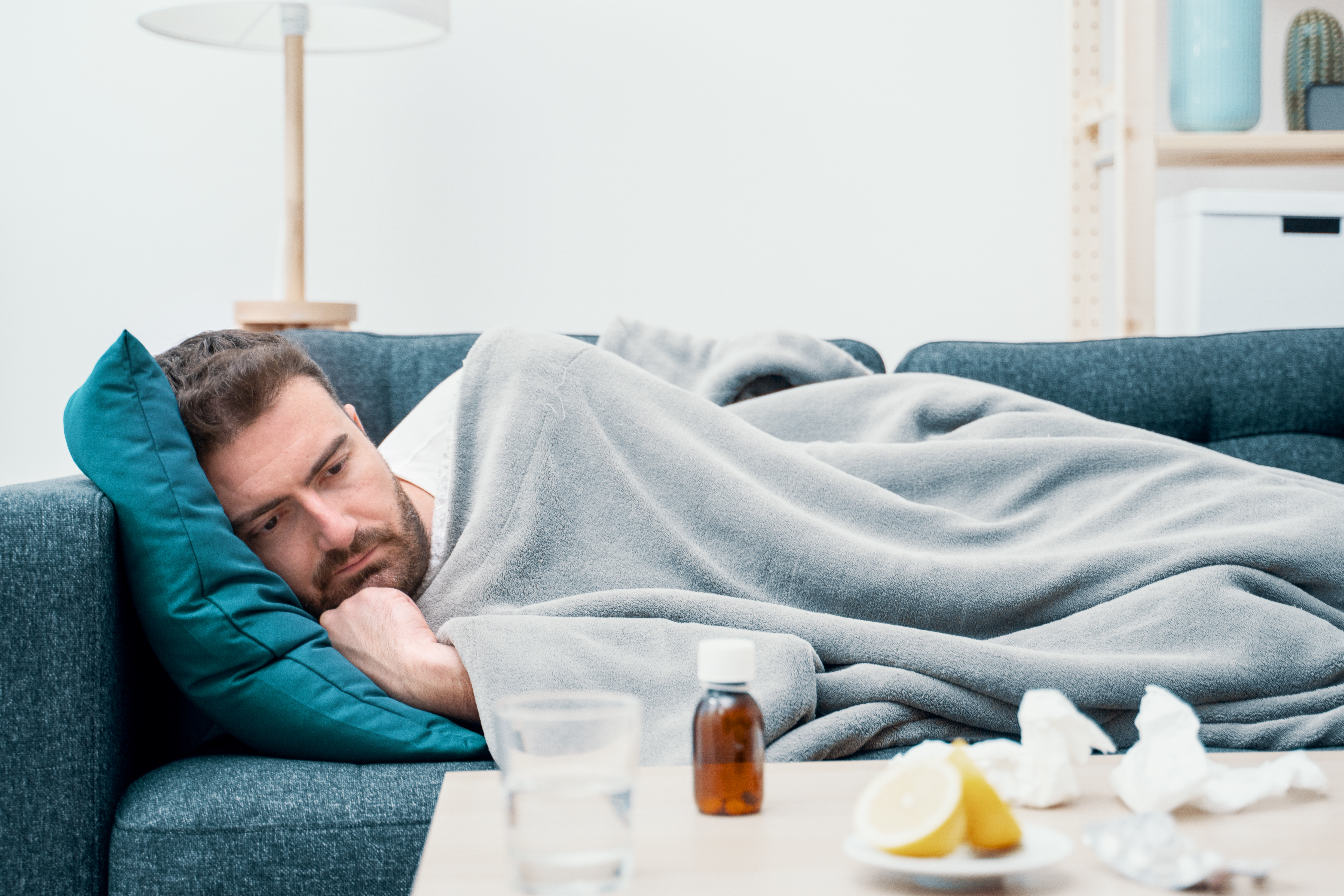 A sick man rests on a couch | Source: Shutterstock