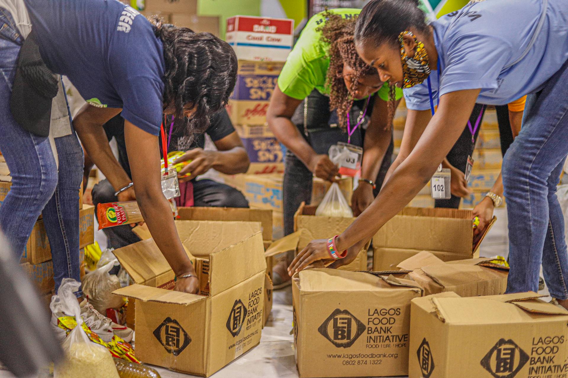 Volunteers at a food bank packing items inside cardboard boxes | Source: Pexels