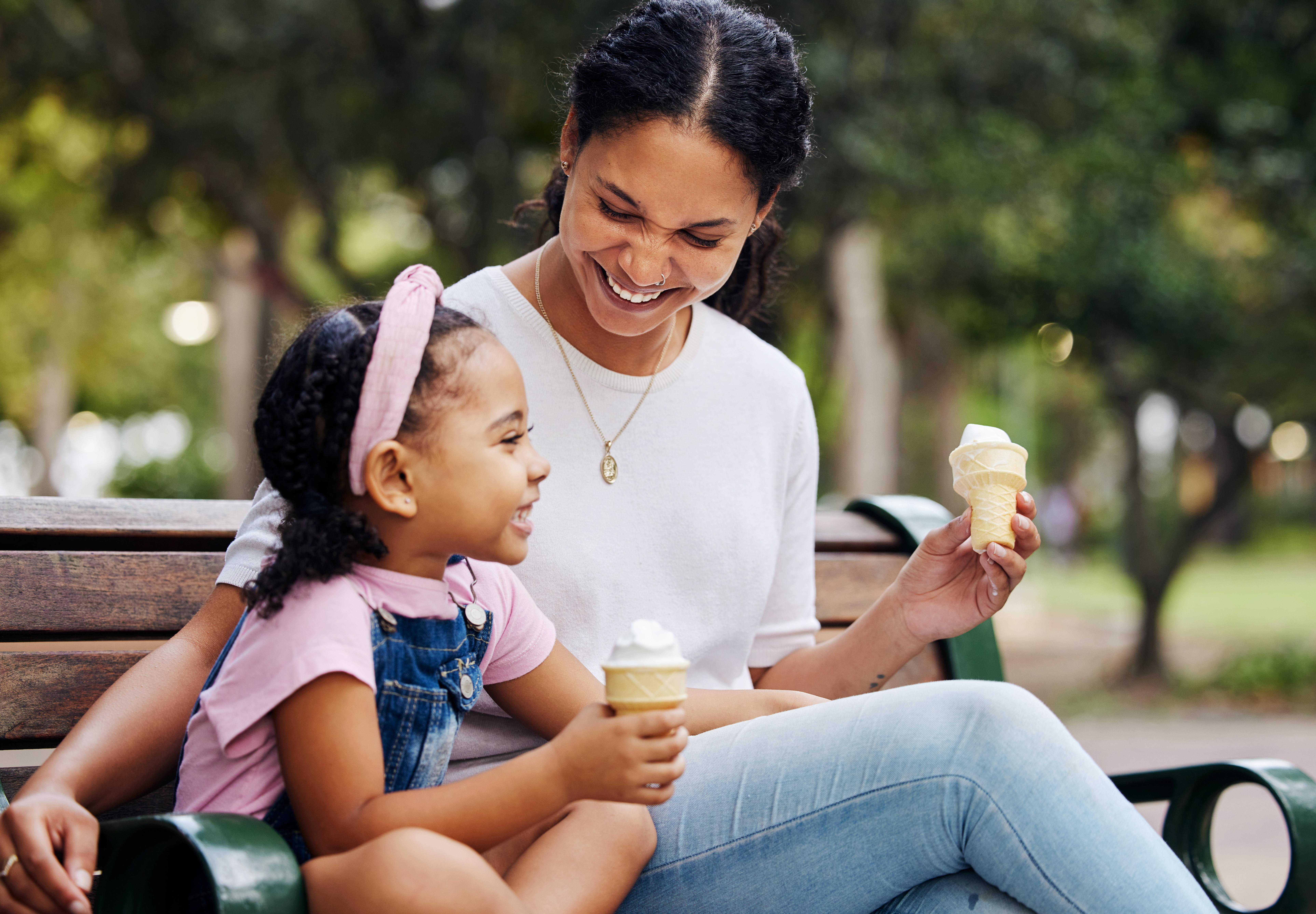 A mother and daughter having ice cream on a park bench | Source: Getty Images