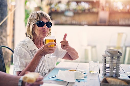 Photo of an old woman enjoying glass of cold beer in restaurant. | Photo: Getty Images